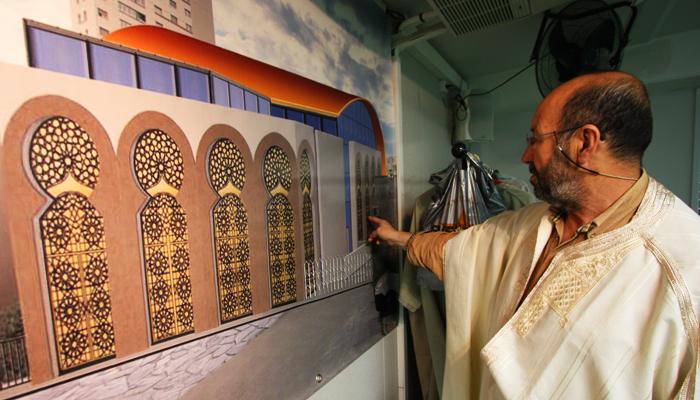 Un fidèle devant le plan de la future mosquée montre le mur mitoyen de la synagogue