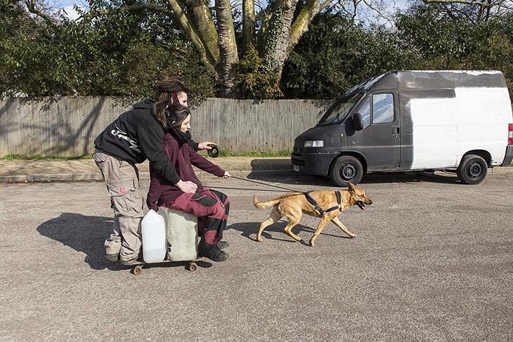 Mika pose les bidons sur le skate et se fait tirer par le chien jusqu’au point d’eau
