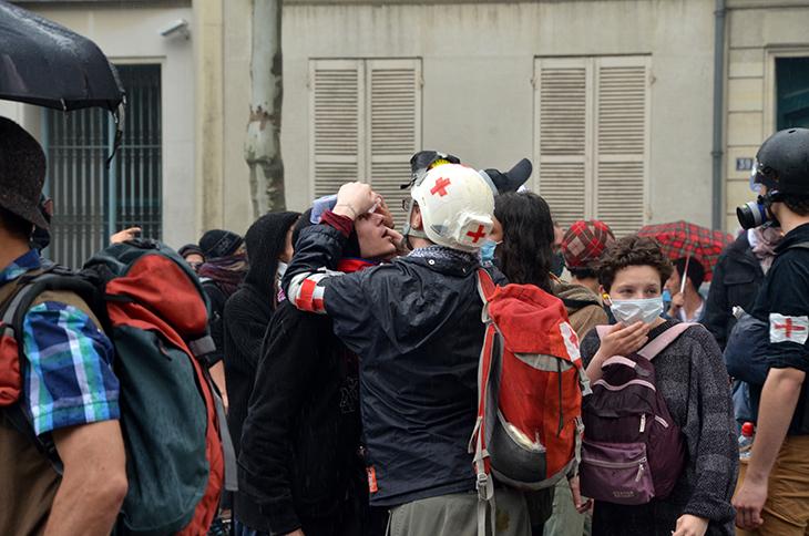 Un Street Med' met du sérum physiologique dans les yeux d'un manifestant gazé.