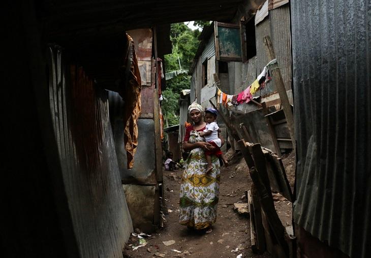 Une femme marche dans les ruelles étriquées du bidonville de Kawéni, son enfant dans les bras.