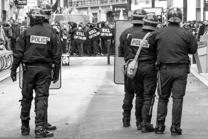 Membres d'une compagnie départementale d'intervention lors d'une manifestation contre la Loi Travail. Aux intersections des rues, des manifestants, équipés de boucliers, protègent le cortège d'éventuelles actions des forces de l'ordre. 31 mars 201