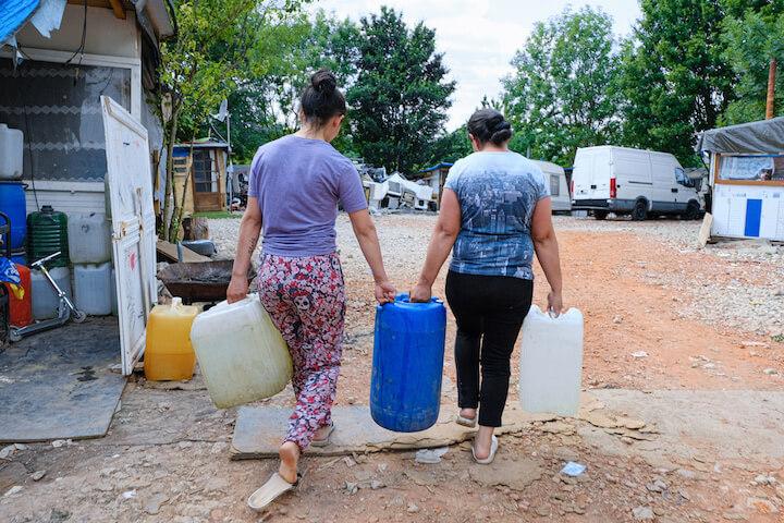 Quand aucun caddie n'est disponible, les femmes portent les énormes bidons d'eau à bout de bras