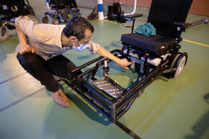 Rabah, un aidant bénévole, fait les derniers réglages sur un fauteuil Strike Force utilisé par l’un des joueurs.