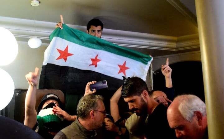 Un petit groupe de militants syriens est venu perturber le colloque avec des chants révolutionnaires et des drapeaux de l’opposition