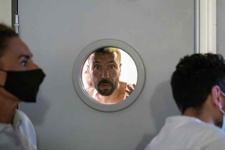 Mourad à travers le hublot de la porte de la salle de vie