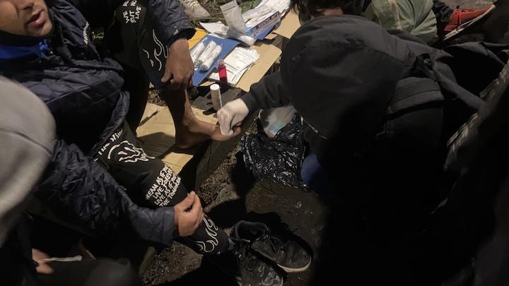 Anna Margueritat, photographe militante présente sur le camp tous les jours, panse les croutes d'un exilé atteint de la gale.