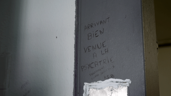 Sur le mur d'une cellule on peut lire : « Bienvenue à la psychiatrie »