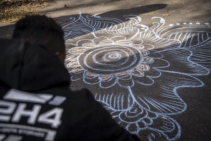 Abdoulaye, jeune ivoirien, termine une arabesque à la craie dans l’une des cours de l’école, qu'il nomme « Les fleurs et l’étoile du henné »