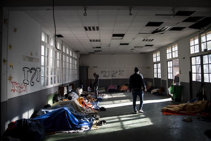 Dans une grande salle, plusieurs jeunes ont installé leurs couvertures pour dormir.
