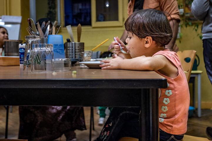 Une des enfants des Youssef et Sarah, mange les plats préparés par les enseignants et les parents d'élèves.