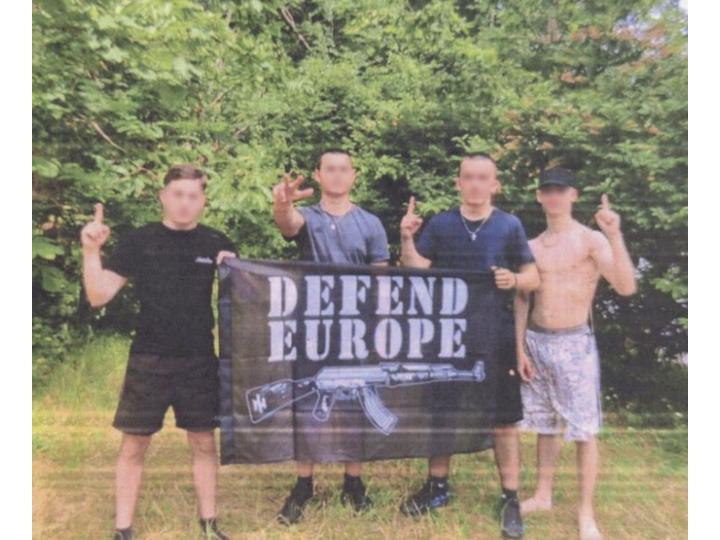 Dans un téléphone, les policiers trouvent une photo des deux Alexandre qui tiennent un drapeau identitaire « Defend Europe ». Alexandre E. y fait un salut de Kühnen, ersatz de salut nazi, tandis que Alexandre H. fait un signe islamiste repris par le Gud.