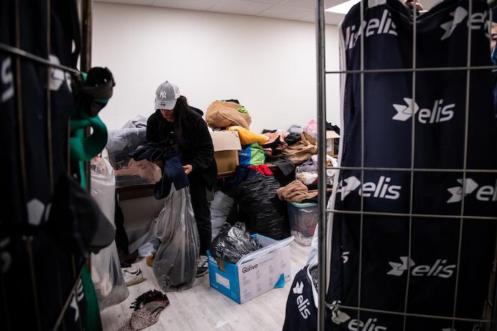 Près d’une salle de réunion du sous-sol de l’hôtel Ibis, aménagée comme espace de repos pour les familles, une pièce déborde de sacs de vêtements et de chaussures