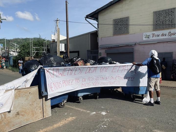 Sur la seule route qui mène à Kaweni, quatre poubelles barrent l'accès aux véhicules. Une banderole « Kaweni est déjà une épave ! Ne nous privez pas du peu qu'on a ! On étouffe ! Nos vies comptent ! » est déployée