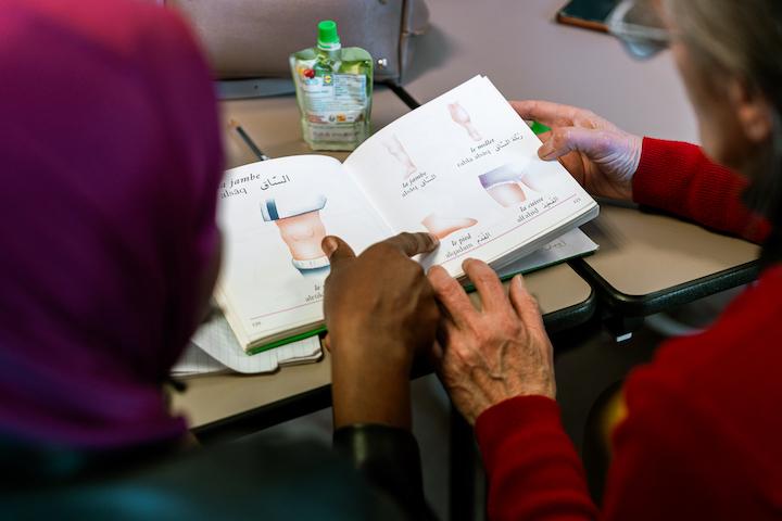 Pascale, bénévole, aide une jeune femme à apprendre le français