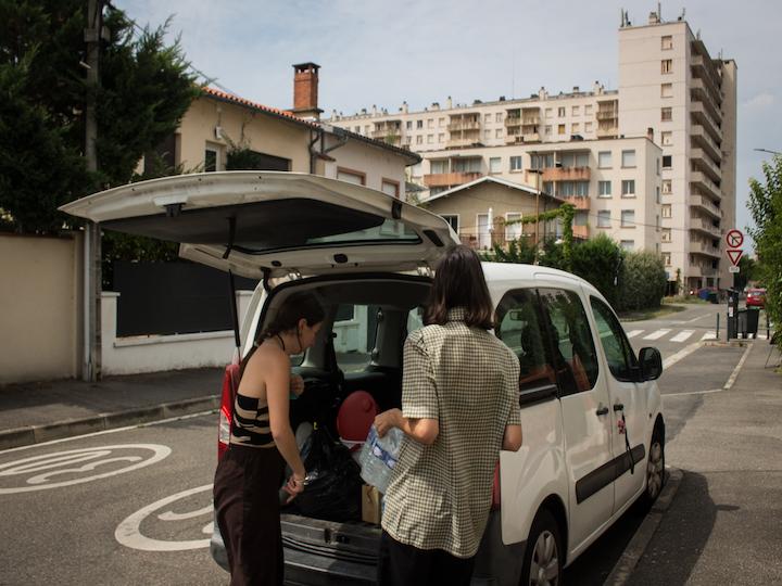 Devant le local, des membres de l'association Utopia 56 chargent leur voiture de bouteilles d'eau.