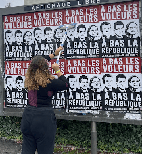 Alors qu'elle est responsable de la section UNI de Mulhouse, Maria L. colle des affiches « À bas la république » avec l'Action française.